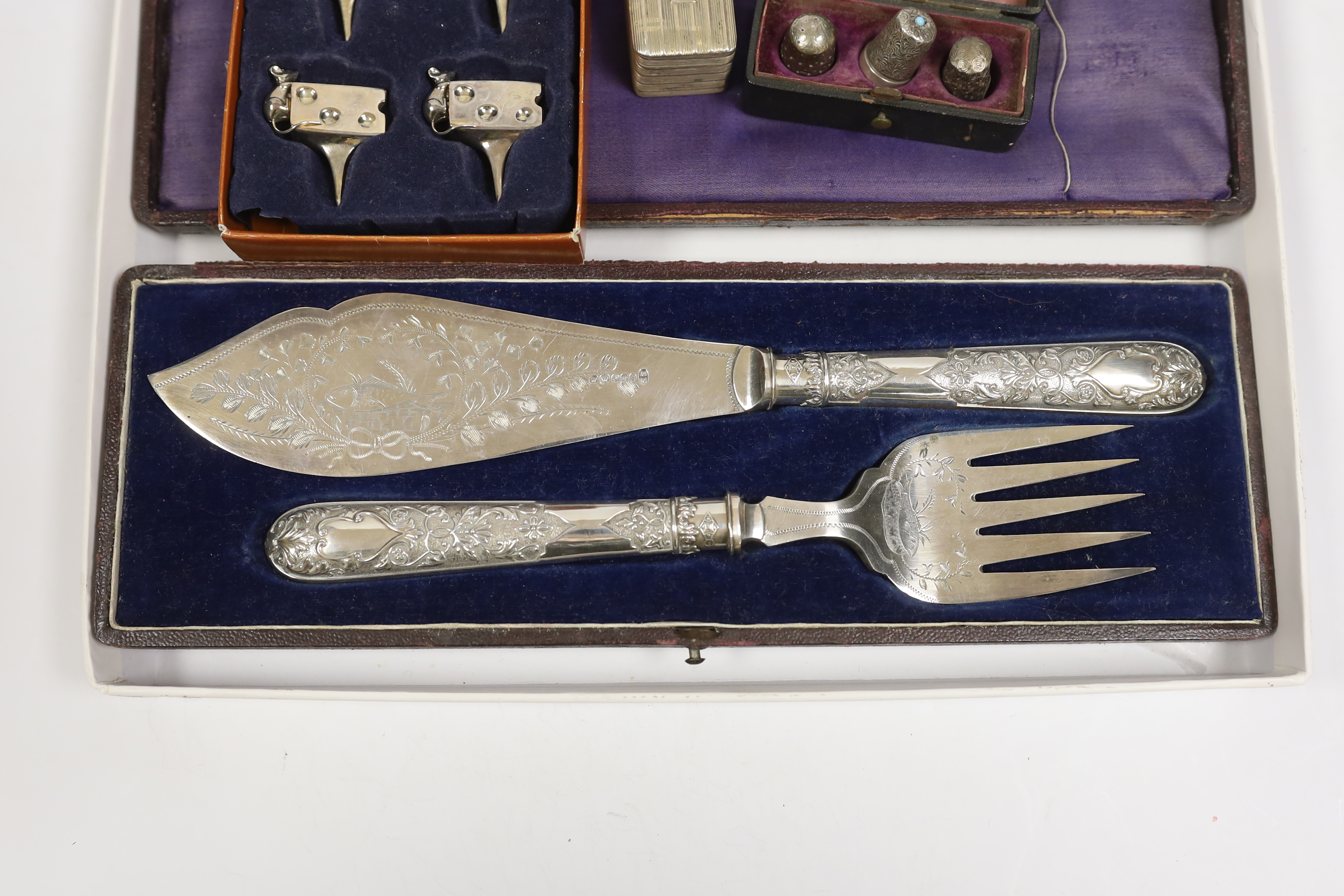 A George III silver nutmeg grater(lacking rasp), Birmingham, 1816, 42mm, together with four assorted thimbles, two silver, a based pair of silver plated fish servers and a set of four metal cheese card holders.